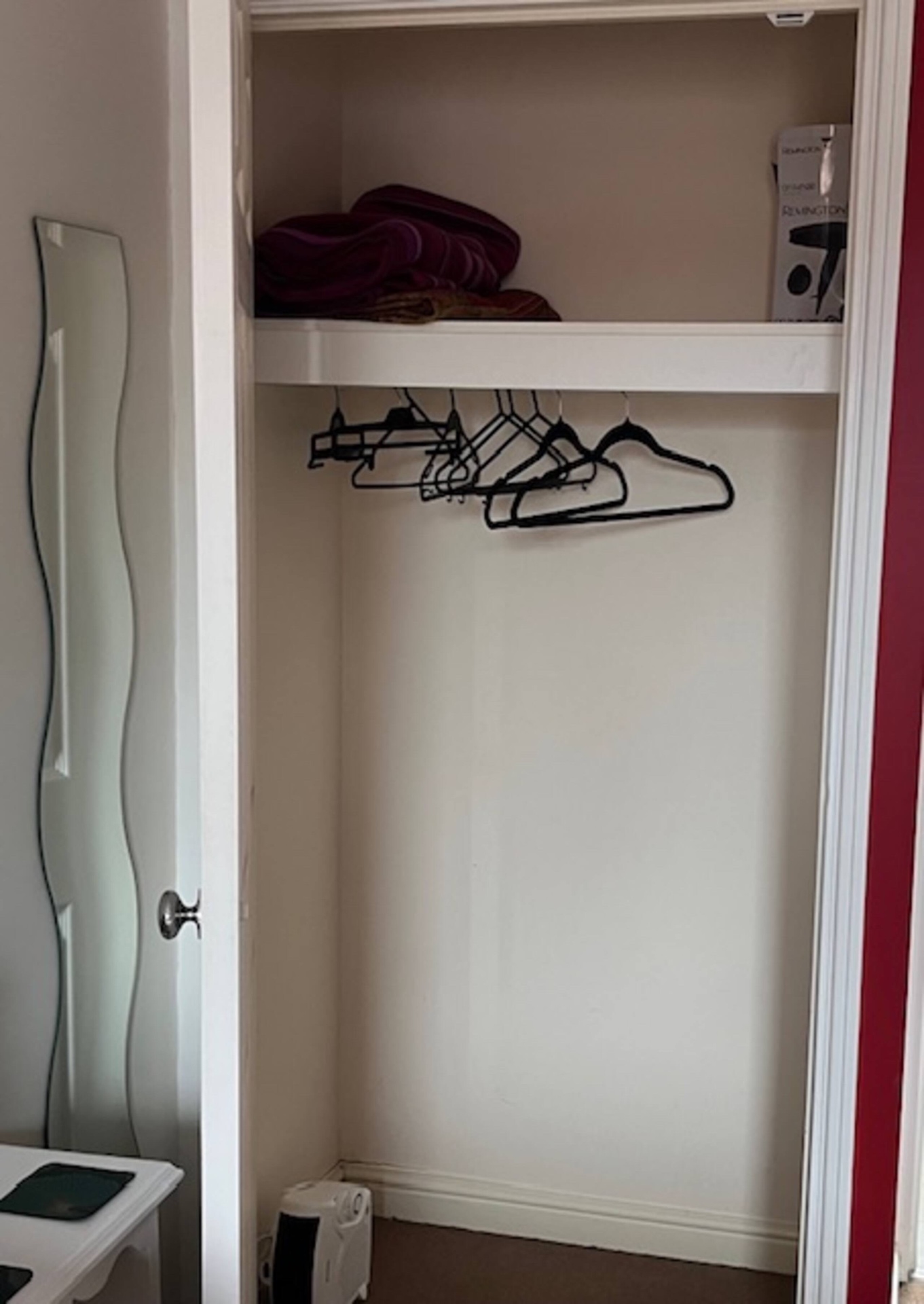 Open wardrobe in the Double Room with hangers, spare towels and a hairdryer on the shelf