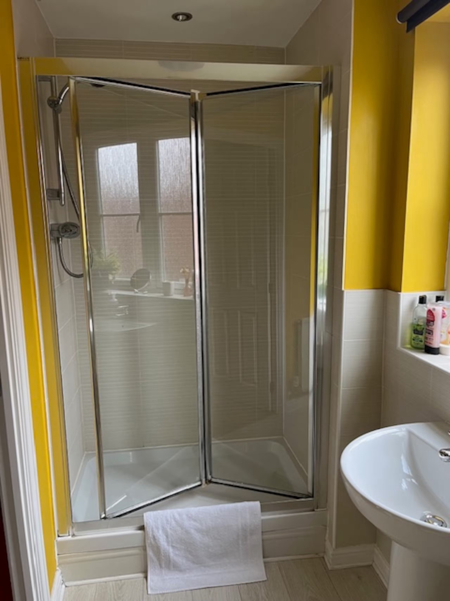 En-suite shower cubicle in the Double Room with folding glass doors and cream tiling