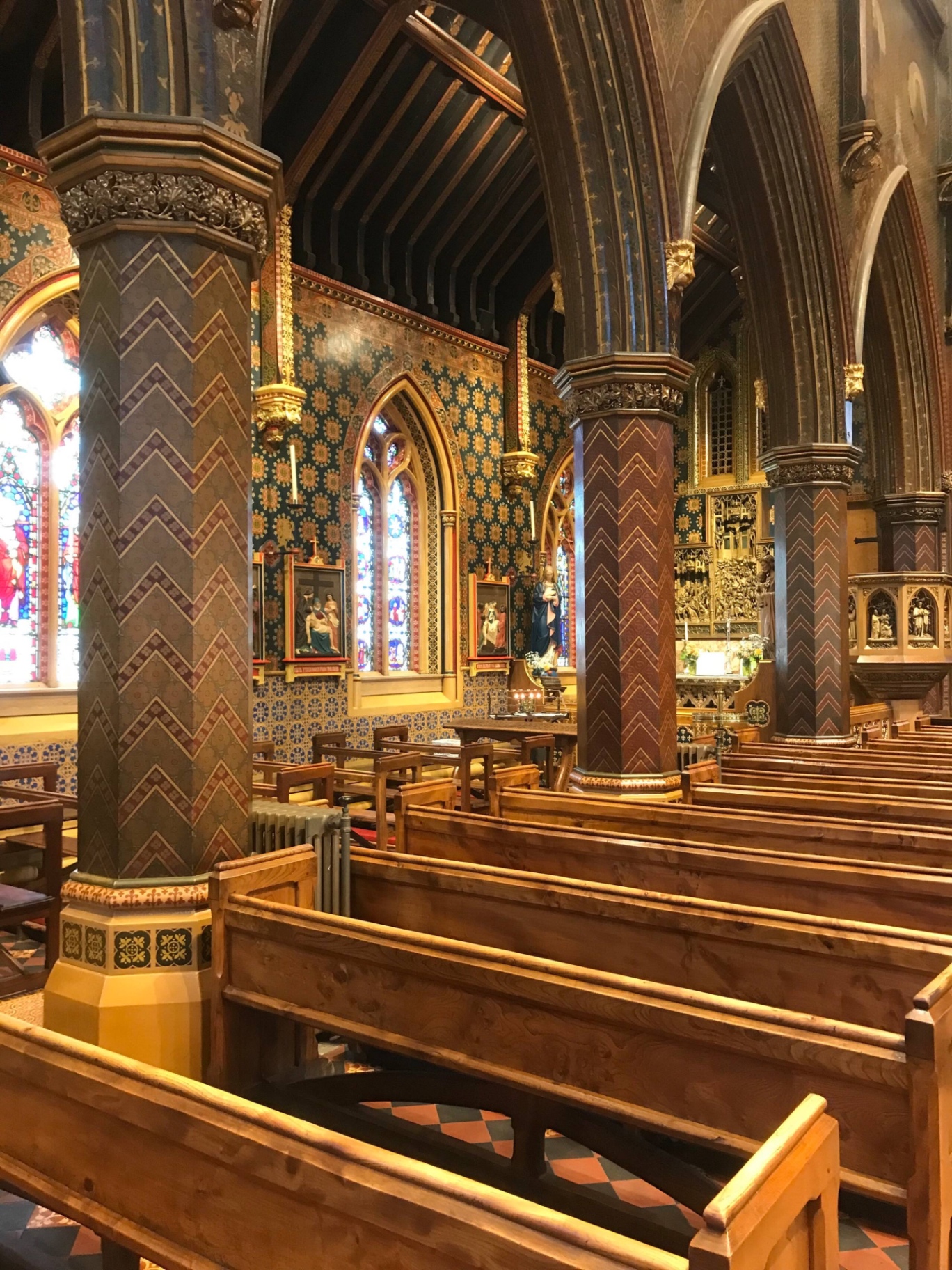 Ornate painted interior of a local church with stained glass and wooden pews