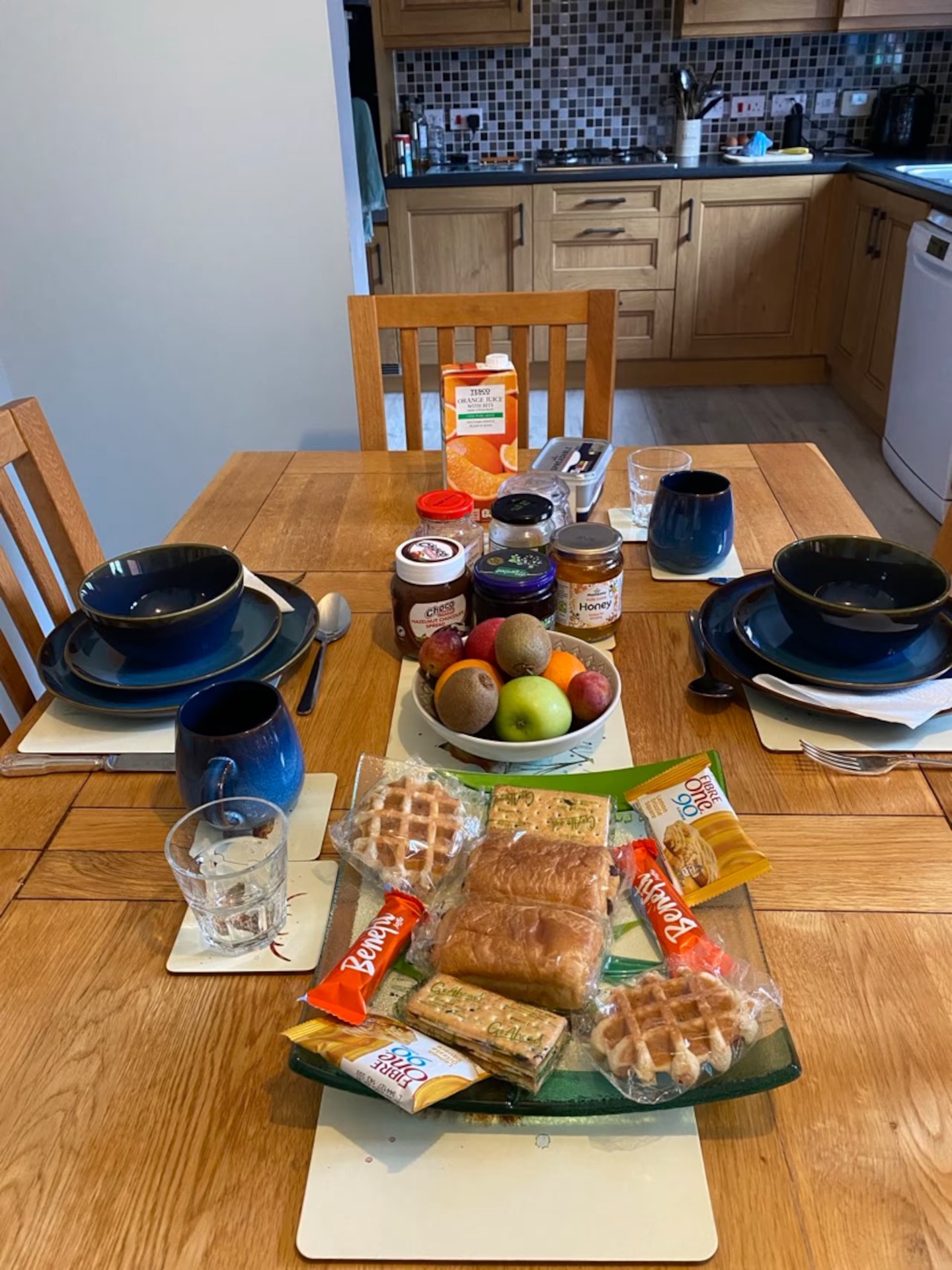 Breakfast table laid with fruit, pastries, jams, honey and juice ready for guests